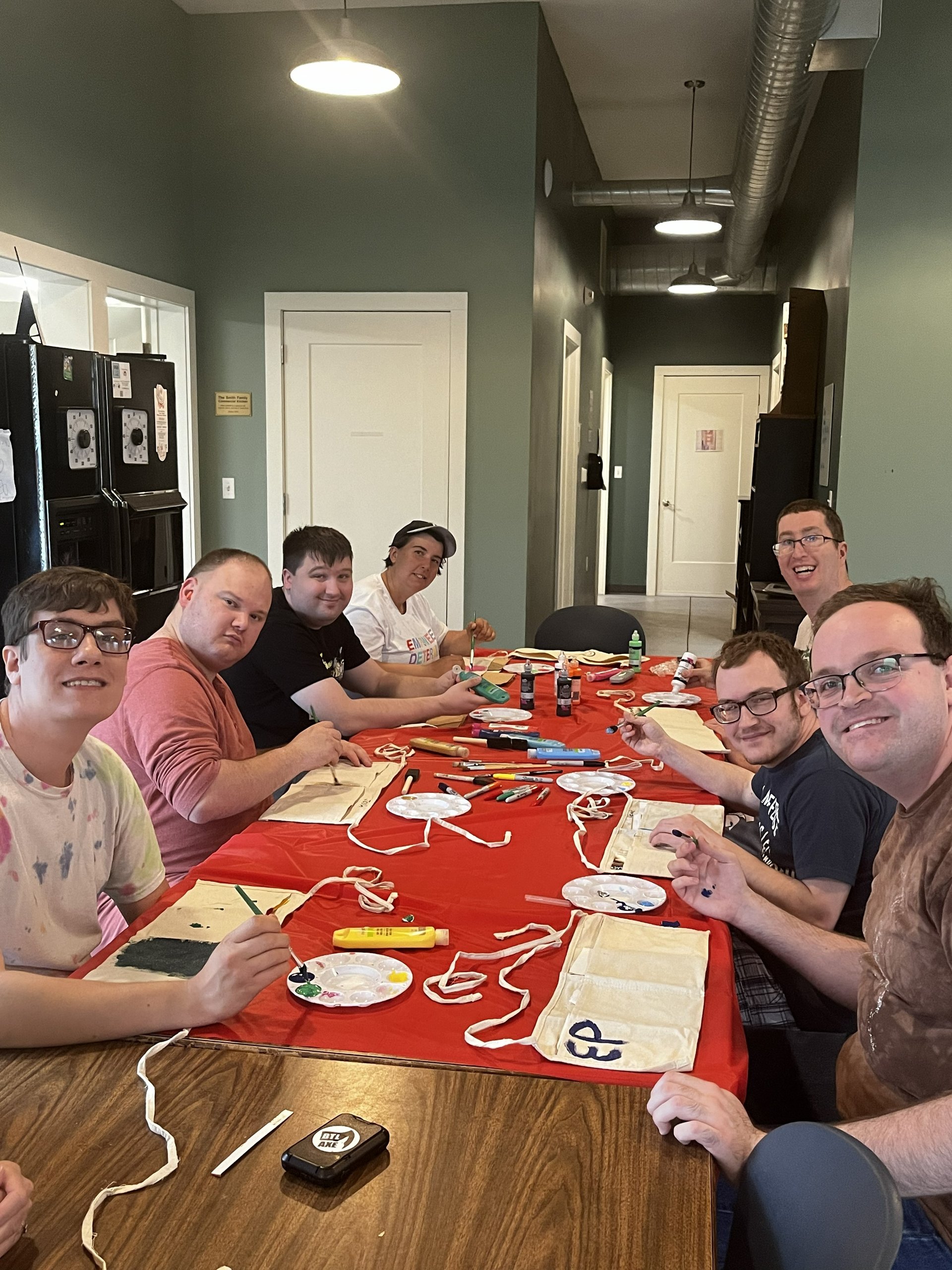 A group of participants sitting at a long table working on a painting craft.