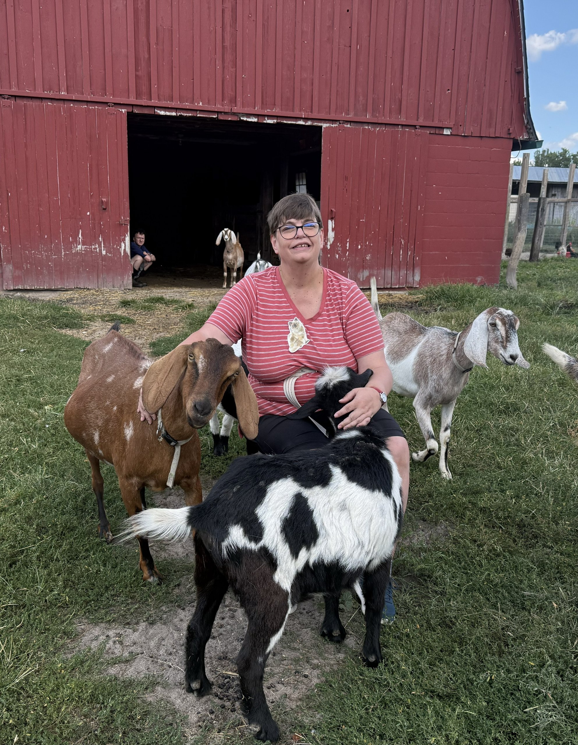 Smiling participant in pasture with goats.