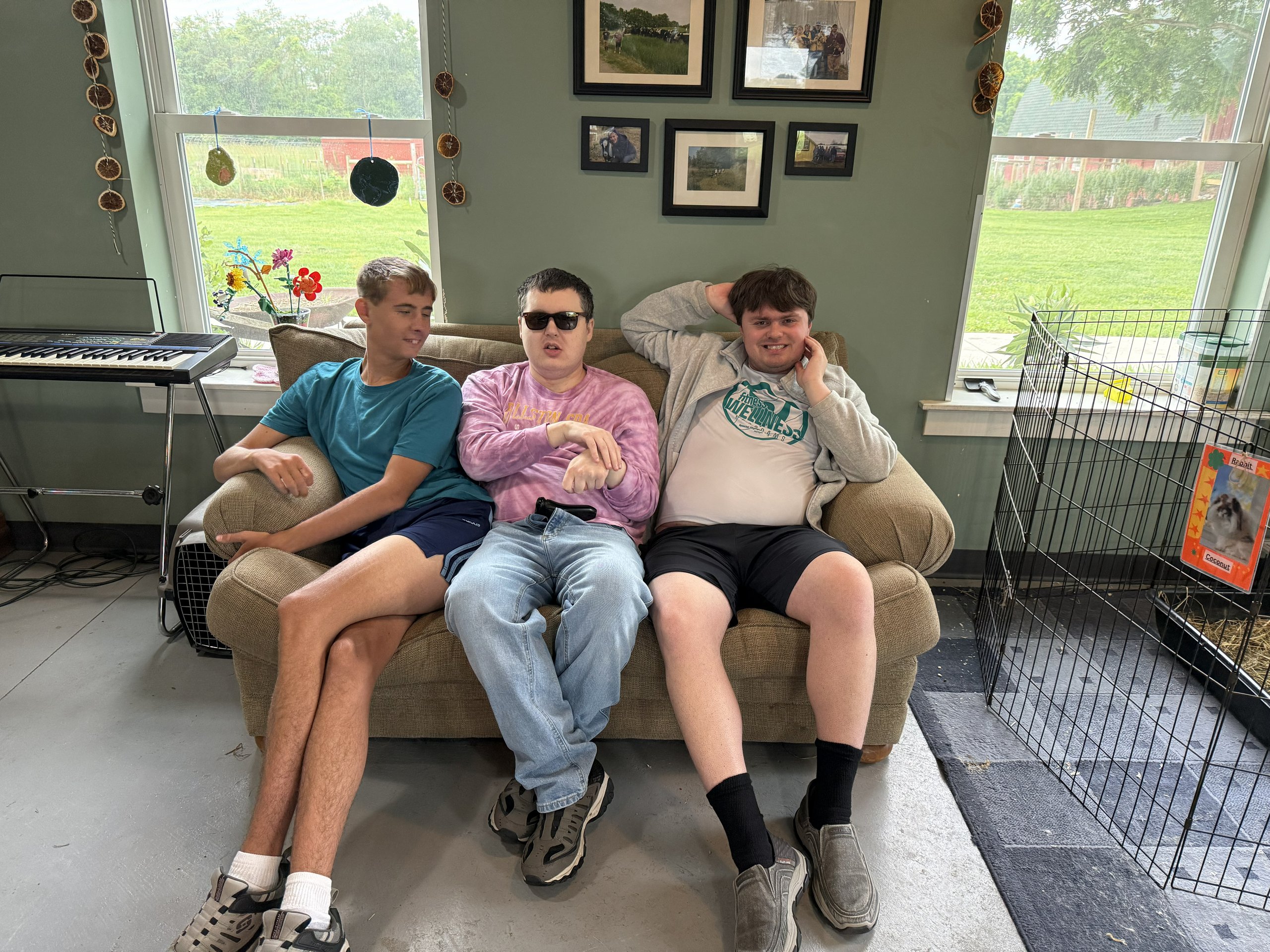 Three friends sit on couch smiling.