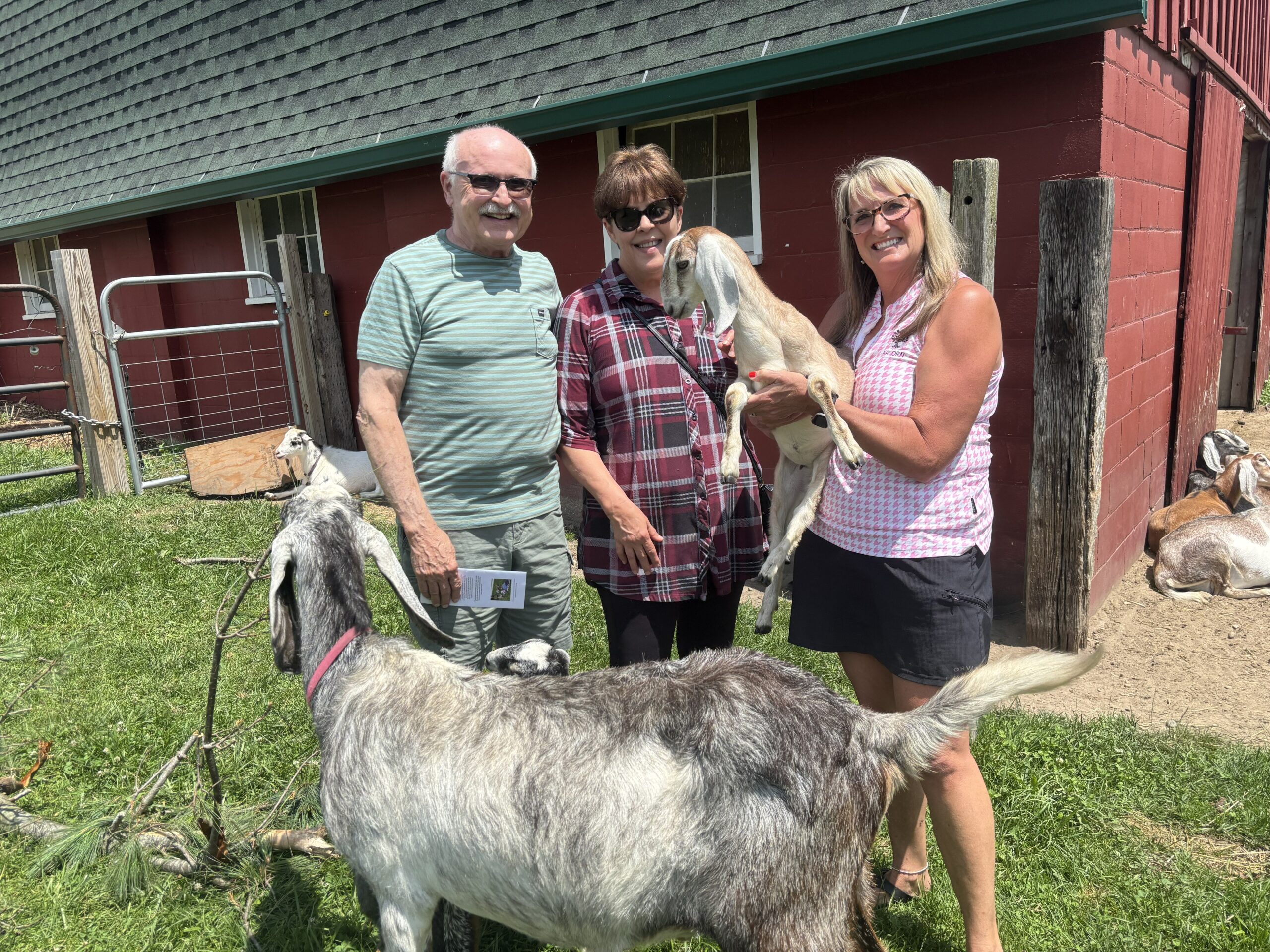 Director of Communications & Community Engagement with farm visitors at AACORN farm in the goat pasture.