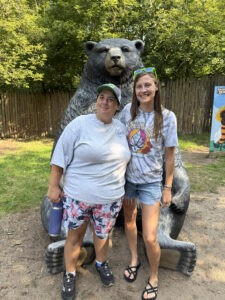 Participant and staff posing in front of bear statue.
