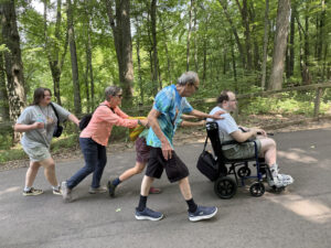 AACORN participants and volunteers helping a participant in a wheelchair navigate Binder Park Zoo
