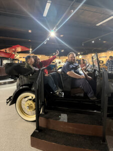 Participants and staff sitting in a classic car